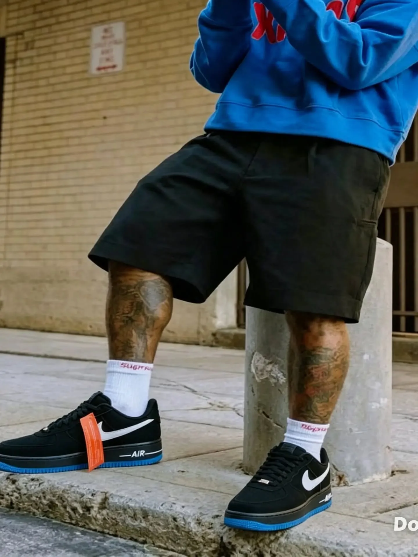 Nike Air Force 1 preto com o detalhe azul, no meio-fio